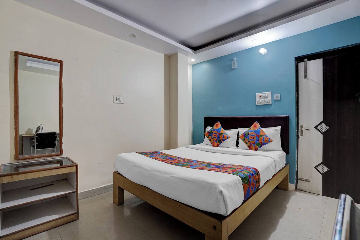 Un dormitorio con cama, espejo, estante y puerta.