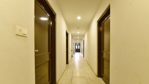 Um corredor longo e estreito com chão de mármore e portas de madeira em ambos os lados.