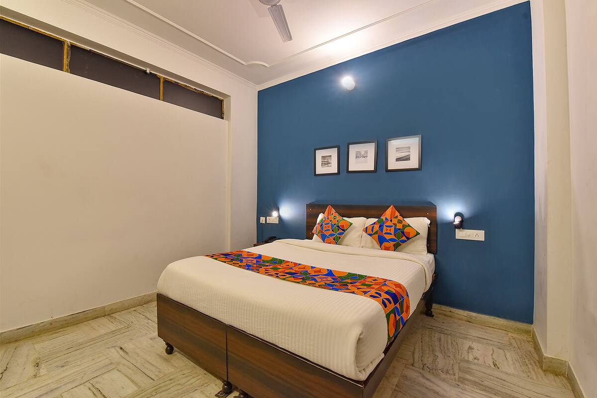 A bedroom with a bed, a blue wall, and three framed pictures.