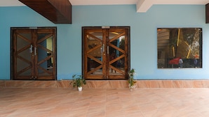 Un vestíbulo con amplias puertas de madera, piso de baldosas y un ventanal con vistas al exterior.