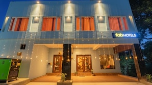 Un hotel moderno con techo plano, ventanas amplias con cortinas y un cartel que dice "Tab Hotels".