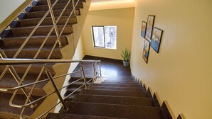 A staircase with metal railings leading to a landing area with a potted plant and framed pictures on the wall. - Fabhotel Red Rose (Guwahati)