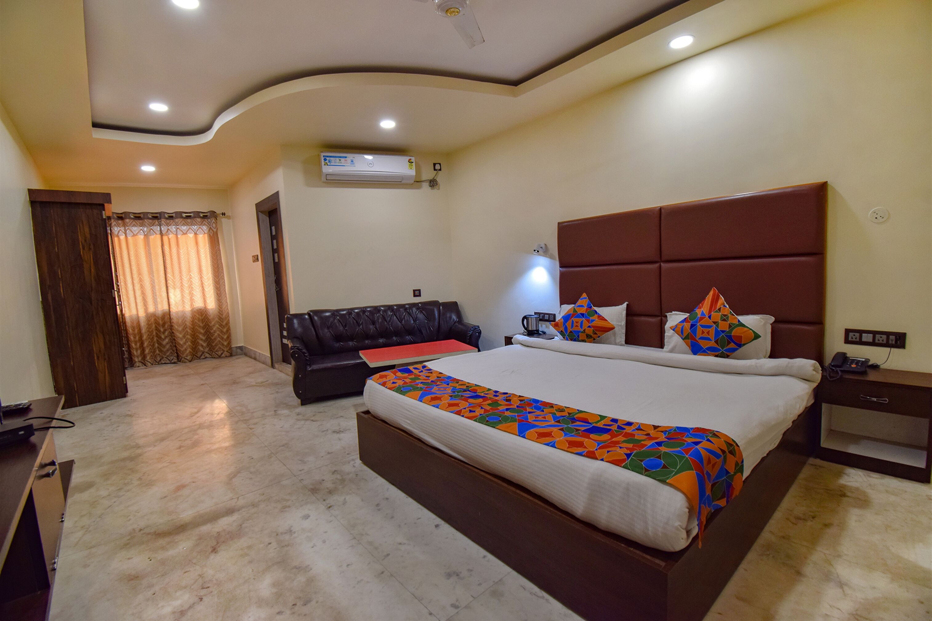 A hotel room with a large bed, a sofa, a desk, and a ceiling fan.