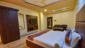 A bedroom with a bed, a wardrobe, a television, and a seating area. - Fabhotel Red Rose (Guwahati)