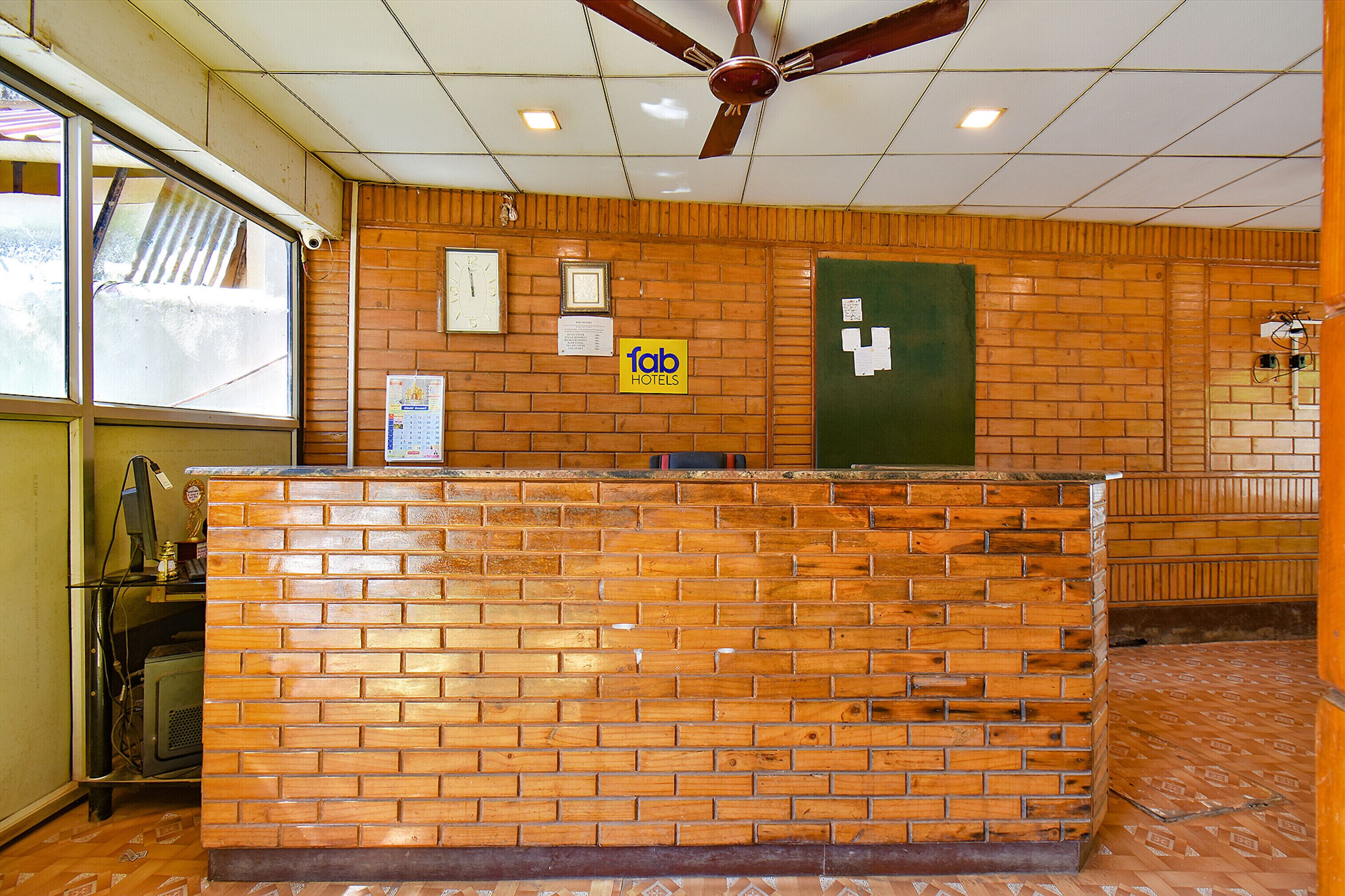 A reception desk with a wooden facade, a ceiling fan, and a green door.