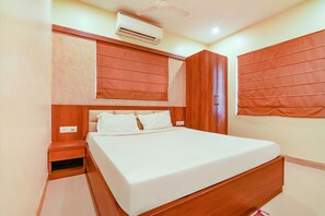 A bedroom with a bed, wooden wardrobe, and an air conditioning unit.