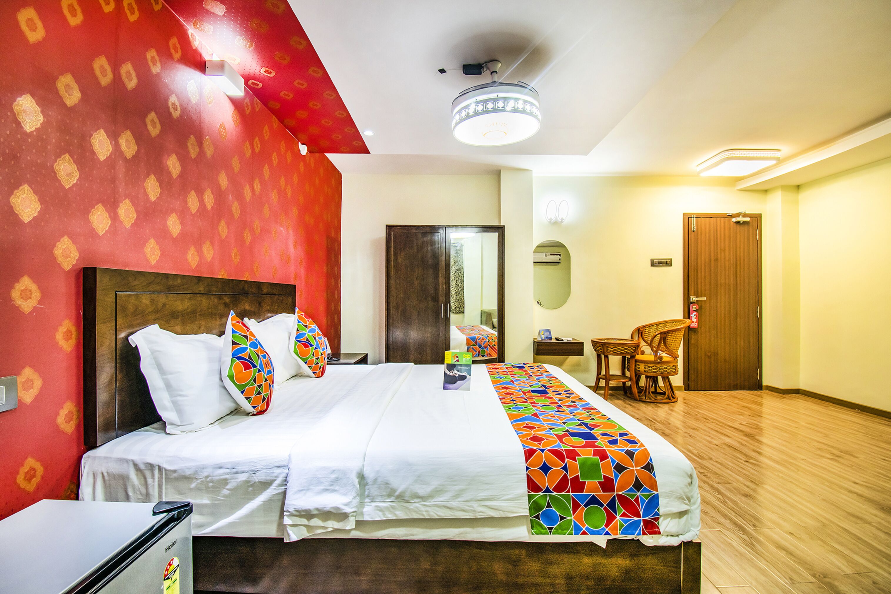Une chambre d’hôtel avec un lit, un bureau, une chaise, un miroir et une porte.