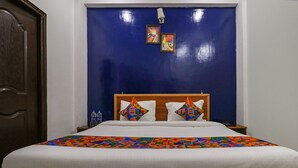 A hotel room with a large bed, a wooden headboard, and a blue accent wall. - Fabexpress Royal Stays (Rishikesh)