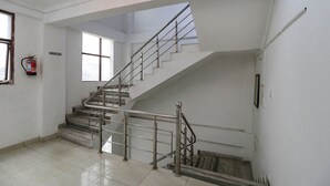 A staircase with metal railings and a fire extinguisher on the wall. - Fabexpress Royal Stays (Rishikesh)