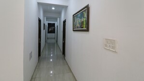 A hallway with a tiled floor, white walls, and a ceiling light. - Fabexpress Royal Stays (Rishikesh)