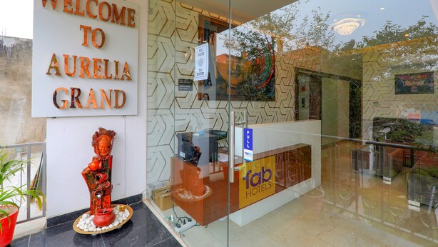 Un mostrador de recepción con un cartel que dice 'Welcome to Aurelia Grand', un cartel que indica 'No Mask' y un cartel con la palabra 'Pull' para una solapa de hotel.