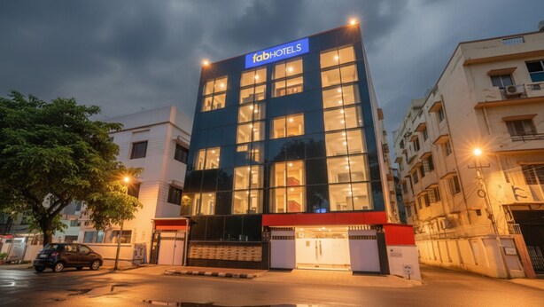 Un moderno edificio de hotel con un letrero llamativo, numerosas ventanas y una entrada protegida por una reja.