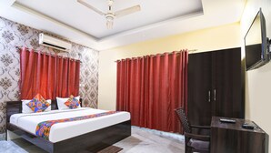 Una habitación de hotel con cama, escritorio, silla, televisor y armario.