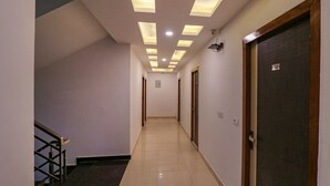 A hallway with a tiled floor, a staircase on the left, and doors on the right. - FabHotel Dolphin International (New Delhi)