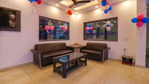 A modern waiting area with two leather sofas, a glass coffee table, and a ceiling fan. - FabHotel Dolphin International (New Delhi)