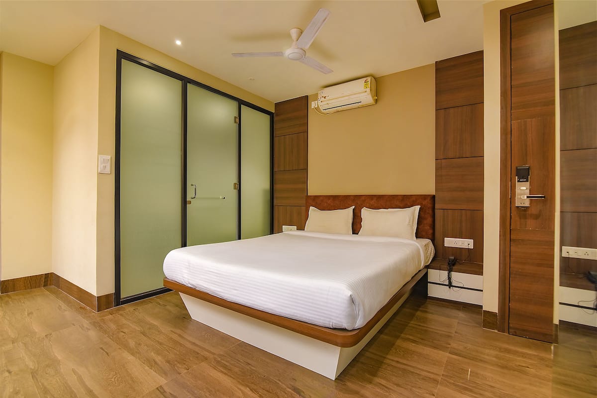 Una habitación de hotel moderna con una cama grande, un ventilador de techo, un equipo de aire acondicionado y un armario corredero.