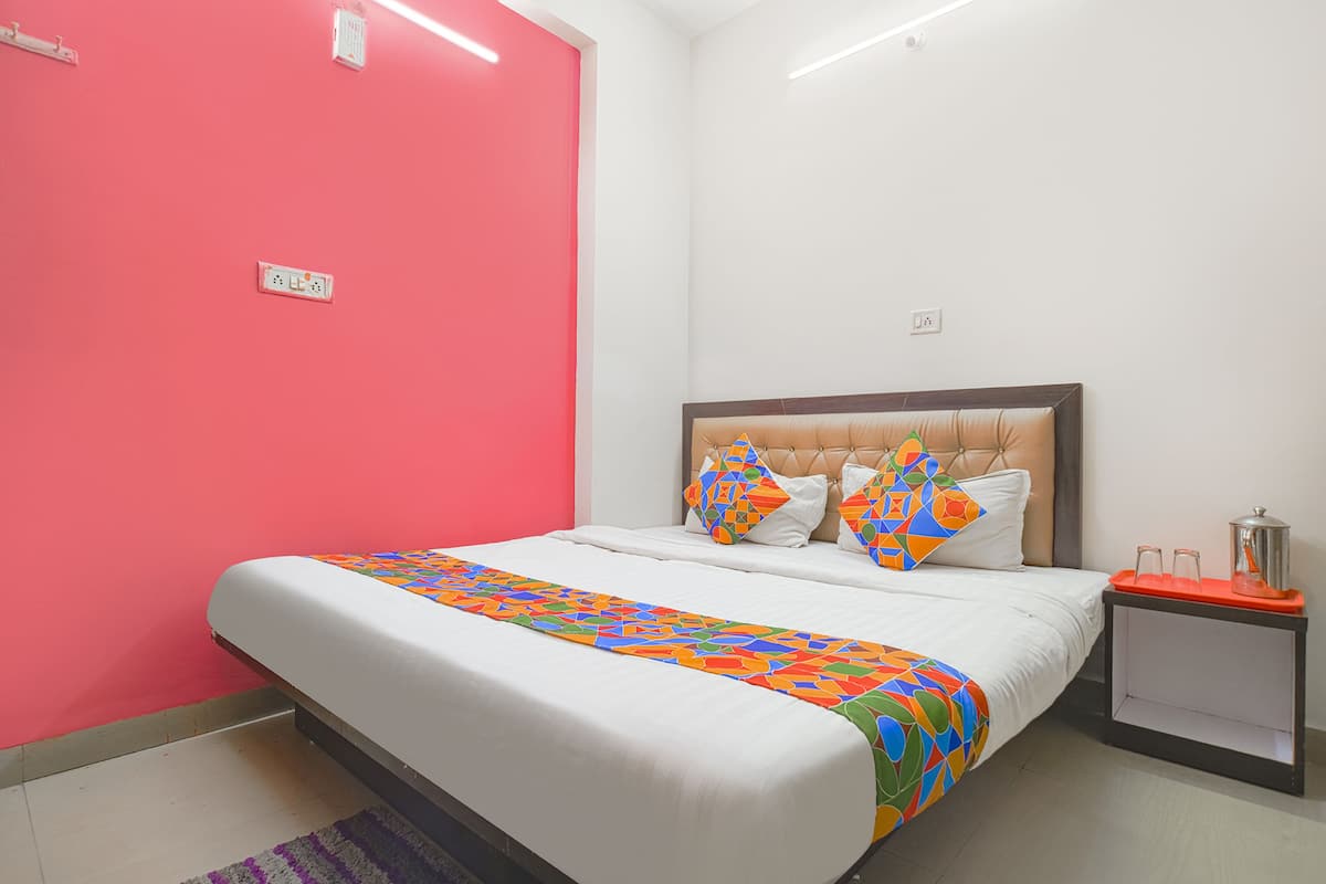A hotel room with a bed, a nightstand, and a red wall.