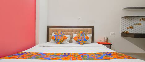 Una cama con un edredón de estampado geométrico colorido, un cabecero capitonado y dos almohadas a juego.