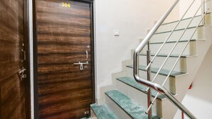 Una puerta de madera con el número 304, una escalera con barandillas de metal y un pasamanos.