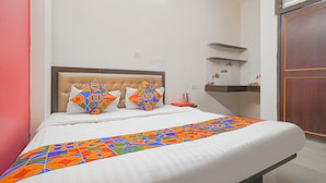 Una cama bien hecha con un edredón colorido, un cabecero y dos almohadones decorativos.