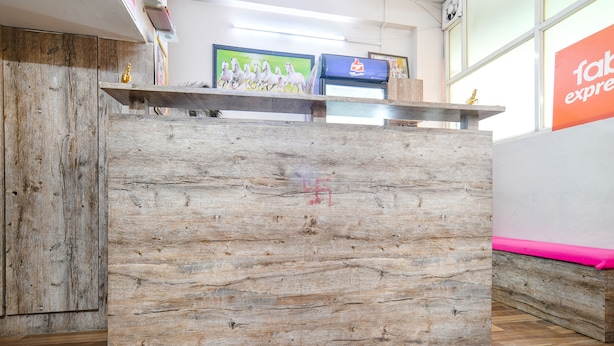 Un mostrador de recepción con detalles de madera, un monitor de computadora y un letrero de 'fab express' al fondo.