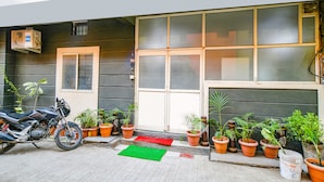 Un edificio con una motocicleta estacionada adelante, una puerta con ventana y varias plantas en macetas.