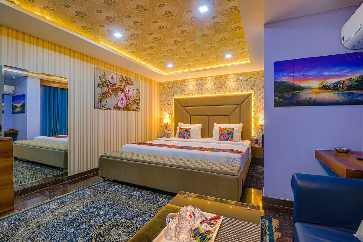 Ein Hotelzimmer mit einem großen Bett, einer Sitzecke inklusive Sofa, einem kleinen Tisch und einem dekorativen Wandbild.