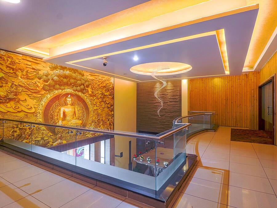 Um interior moderno com guarda-corpo de vidro, uma estátua de Buda e um lustre espiral.