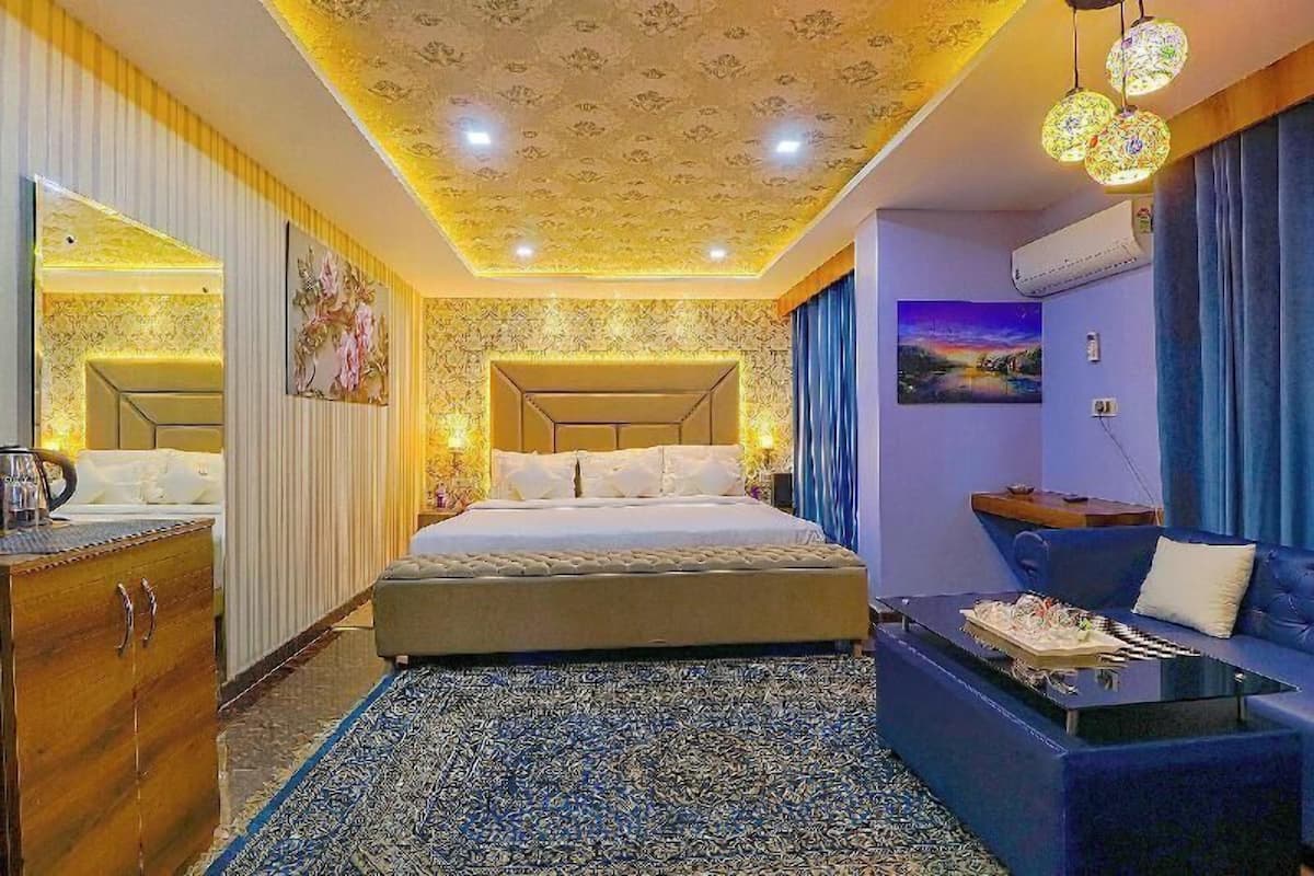 Ein Hotelzimmer mit einem Bett, einem Sofa, einem Couchtisch, einem Schminktisch und einem gemusterten Teppich.