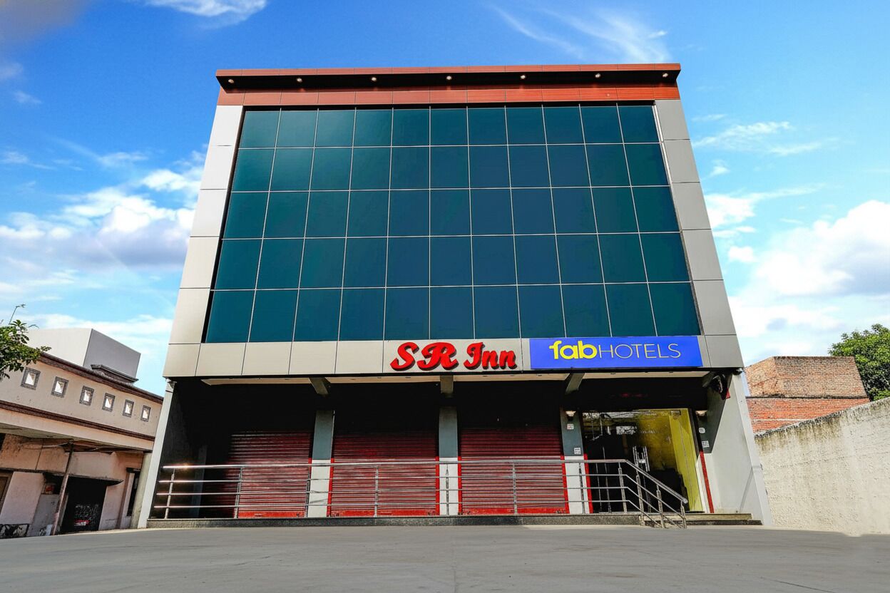 A modern building with a large glass facade, featuring signage for SR Inn and FabHotels.