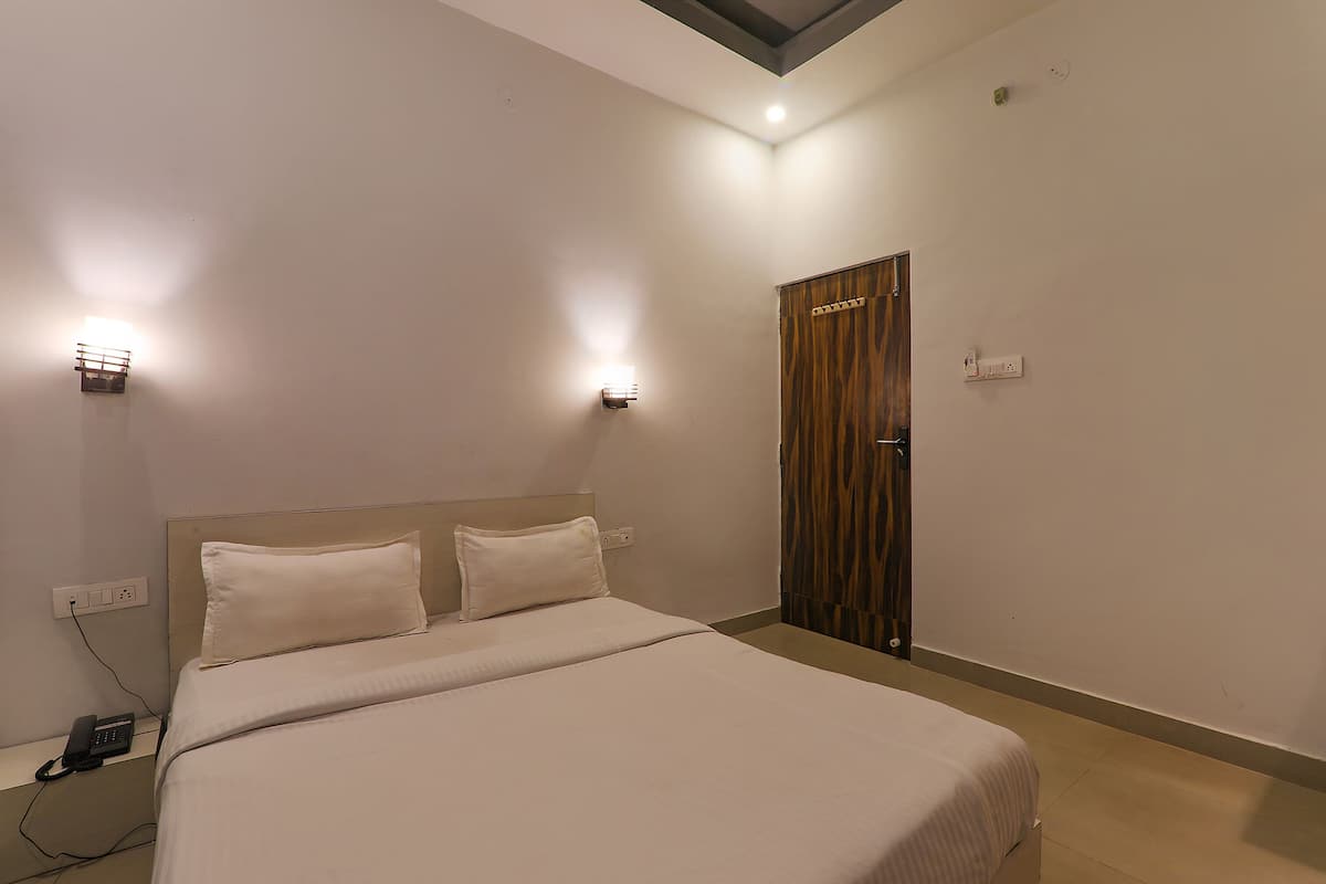 Un dormitorio con cama, lámparas de noche, teléfono y puerta.