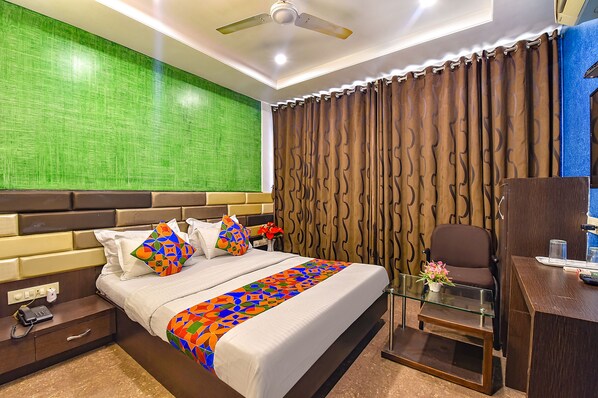 A hotel room with a bed, a desk, a chair, a telephone, and a curtain.