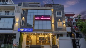 Un hotel moderno con un letrero destacado que dice 'Hotel Pinkcity Prime' y señalización de 'Fab Hotels'.