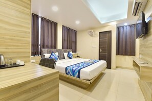 Una habitación de hotel con cama, escritorio, silla, televisor y ventilador de techo.