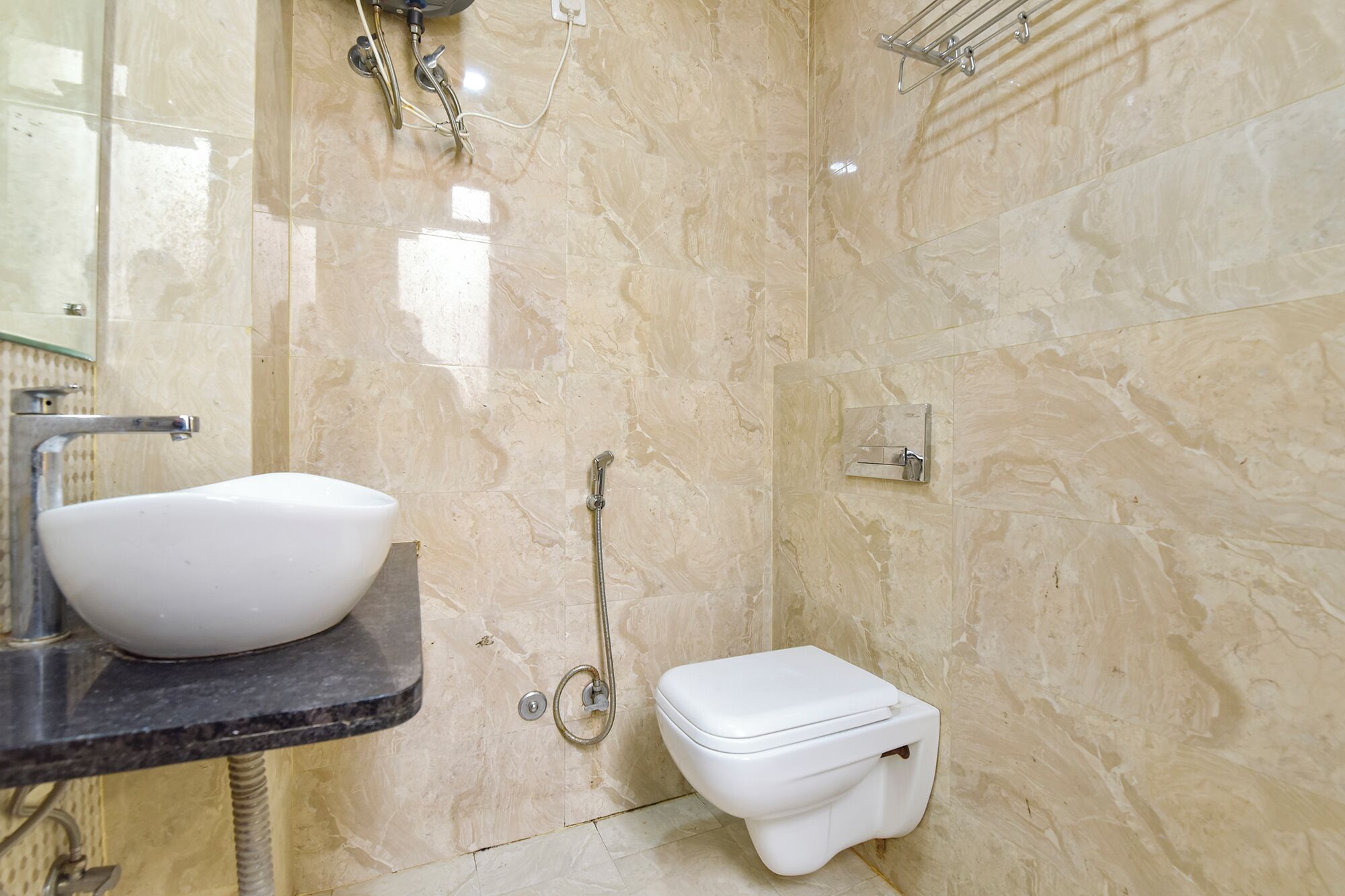A bathroom with a marble floor, a white sink, and a toilet.
