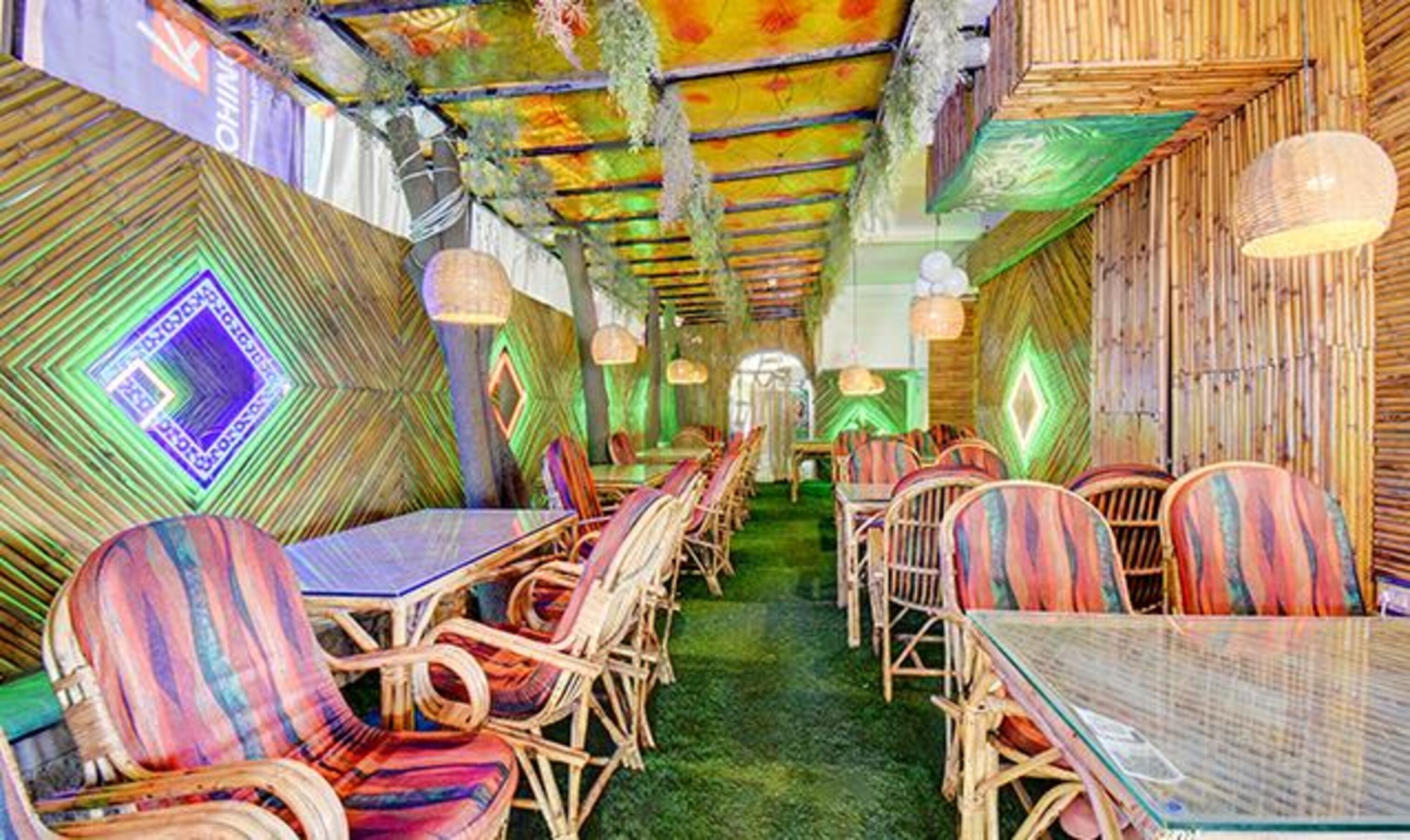 A restaurant with a long table and chairs, bamboo walls, and hanging lights.