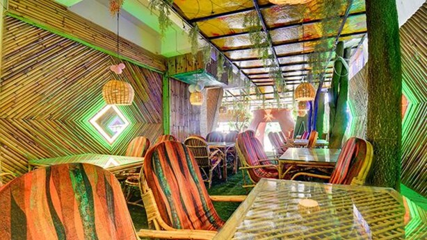 Un restaurante con paredes de bambú, sillas a rayas y una mesa de cristal.