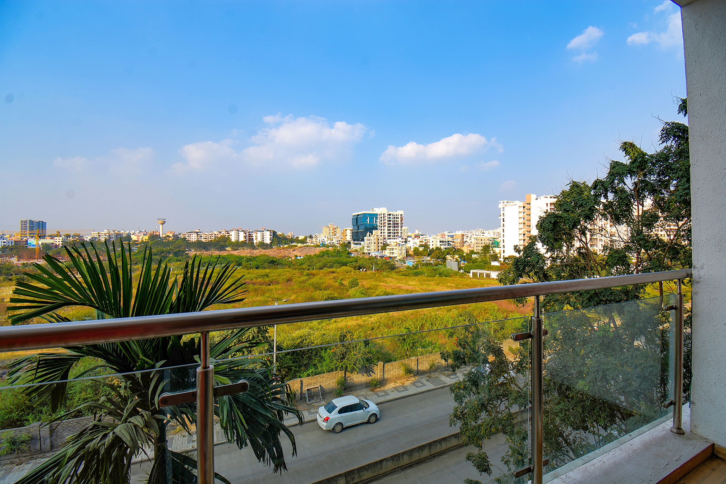 Un balcón con vistas a un paisaje urbano, incluyendo edificios y una calle con un coche.