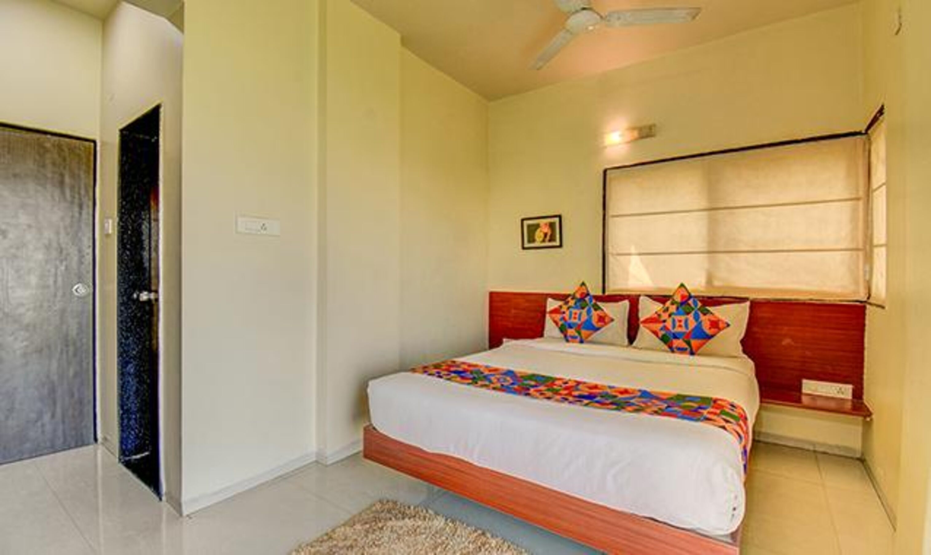 Un dormitorio con cama, ventilador de techo, puerta y ventana con persianas.