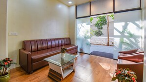Una sala moderna con un sofá de cuero marrón, una mesa de centro de vidrio y una planta en maceta.