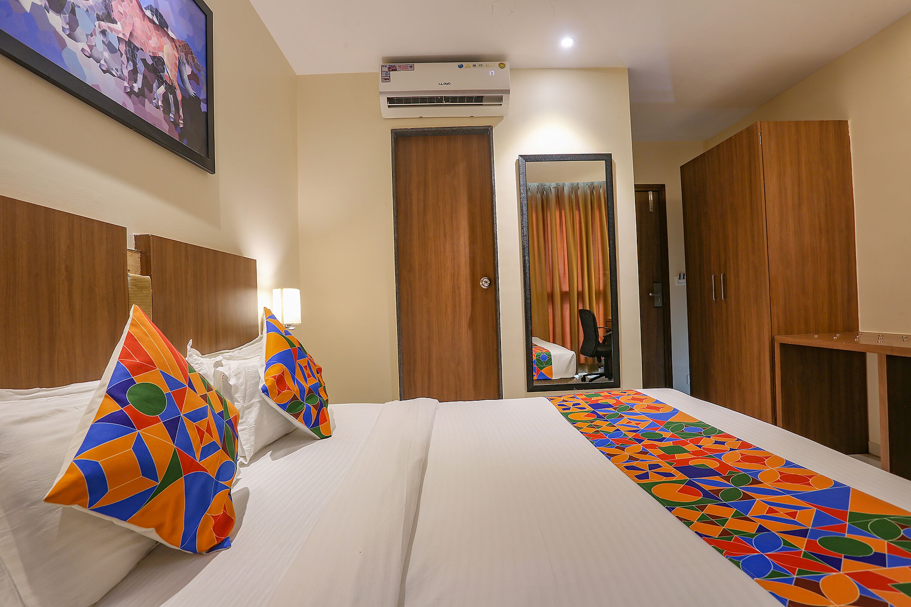 Une chambre d’hôtel équipée d’un lit, d’oreillers, d’un miroir, d’une armoire et d’un appareil de climatisation.