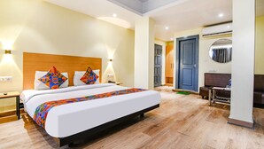 Una habitación de hotel con cama, mesitas de noche, escritorio y aire acondicionado.