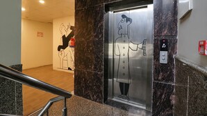 Ein Aufzug mit einer Comicfigur auf der Tür, einem Rauchmelder und einem digitalen Display.