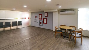 Ein Konferenzraum mit Holztisch und -stühlen, gerahmten Bildern an der Wand und einer Klimaanlage.