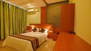 Una habitación de hotel con una cama grande, una mesita de noche de madera, un escritorio y una pared decorativa de piedra.