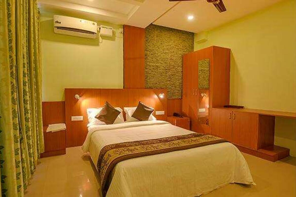 Quarto de hotel com cama, guarda-roupa, penteadeira e ar condicionado.