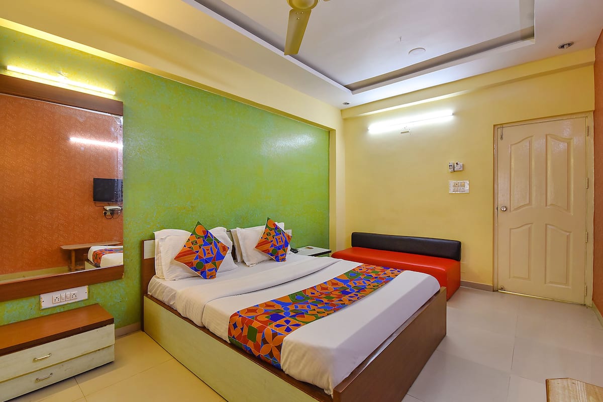 Una habitación de hotel con una cama, una mesita de noche, un espejo y una puerta.