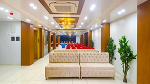 A hotel lobby with a beige sofa, ceiling lights, and a chandelier. - Fabhotel Palash (Danapur)