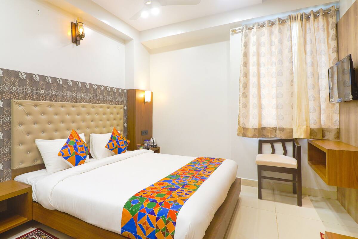 A hotel room with a large bed, a chair, a TV, and a nightstand.