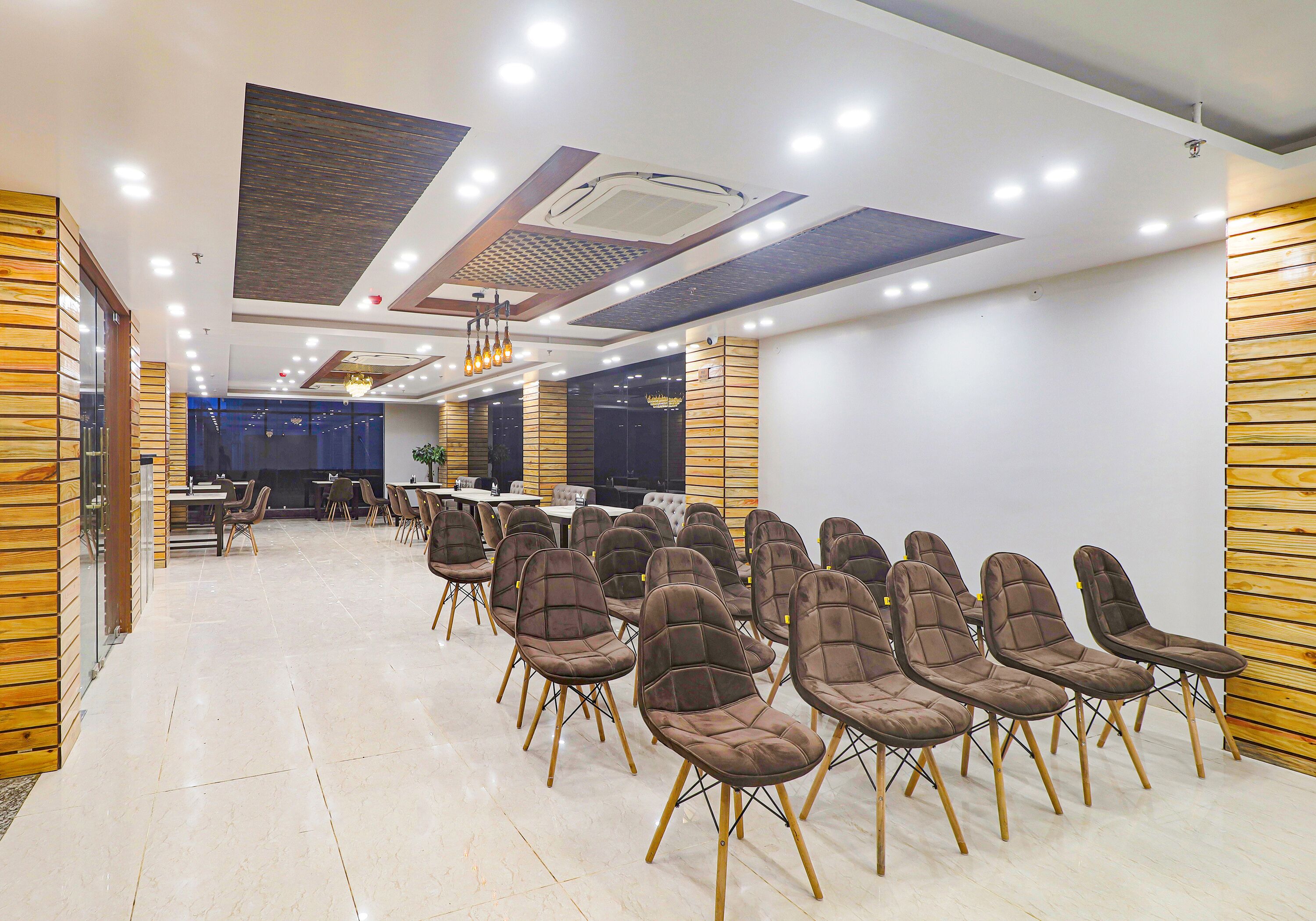Una amplia sala de conferencias con filas de sillas, una larga mesa y un diseño de techo moderno.